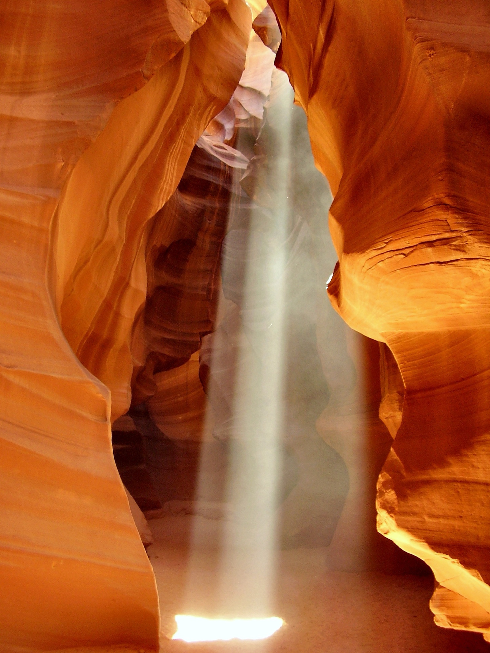 A light beam descends through Upper Antelope Canyon's swirling red sandstone walls